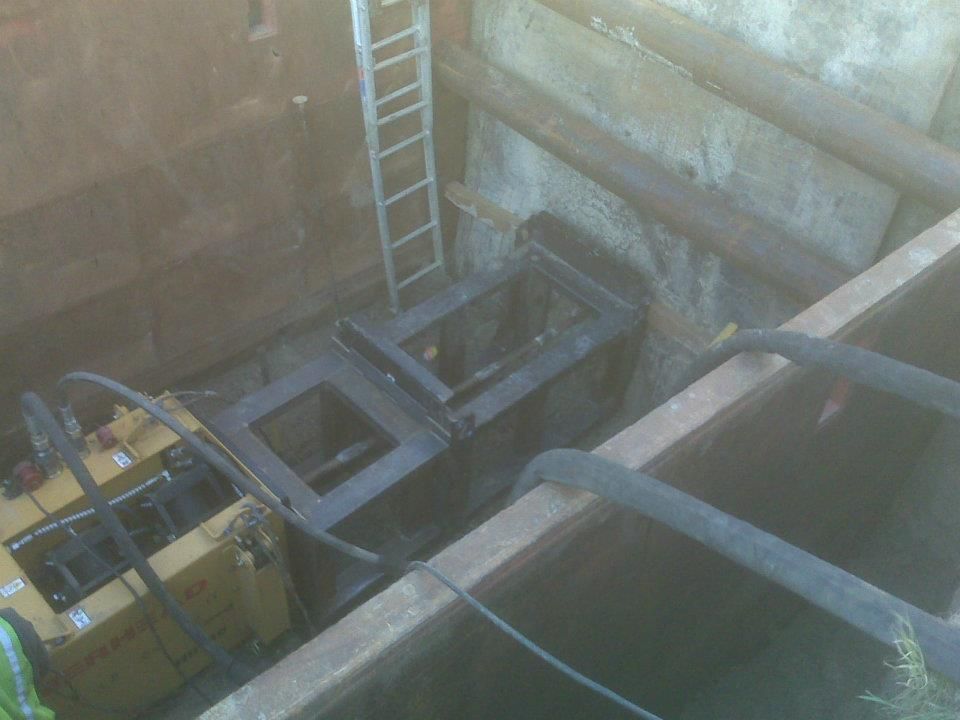 Construction machinery in a deep excavation beside a ladder and concrete walls