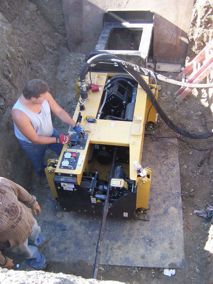 Worker operating a yellow trenching machine in a dirt excavation site