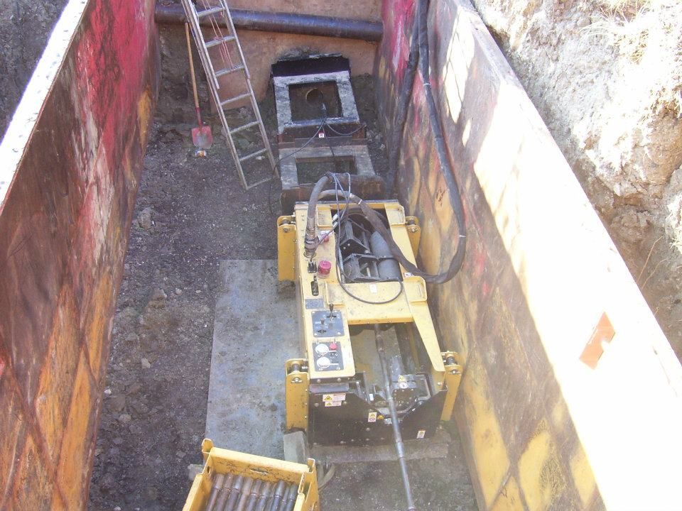 Narrow trench with a yellow generator and ladder in an underground utility shaft