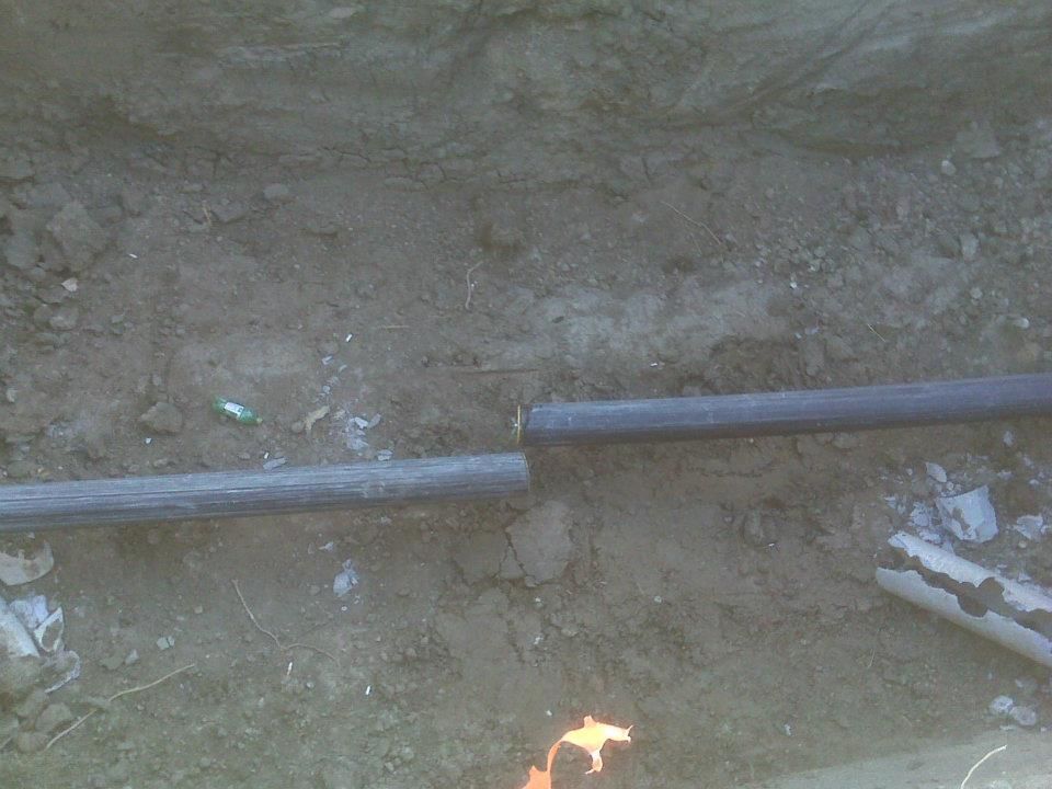 Two metal pipes on dirt ground with a small flame near the bottom center