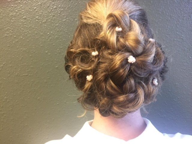 A woman has her hair in a bun with pearls in it