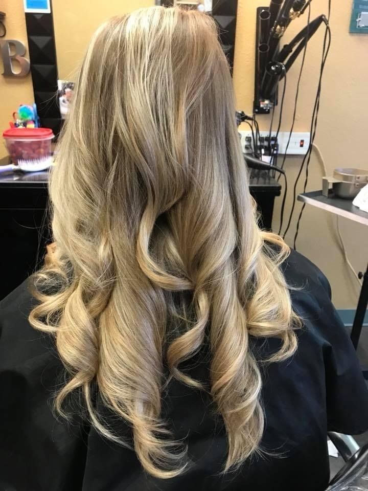 A woman with long blonde hair is sitting in a chair in a salon.