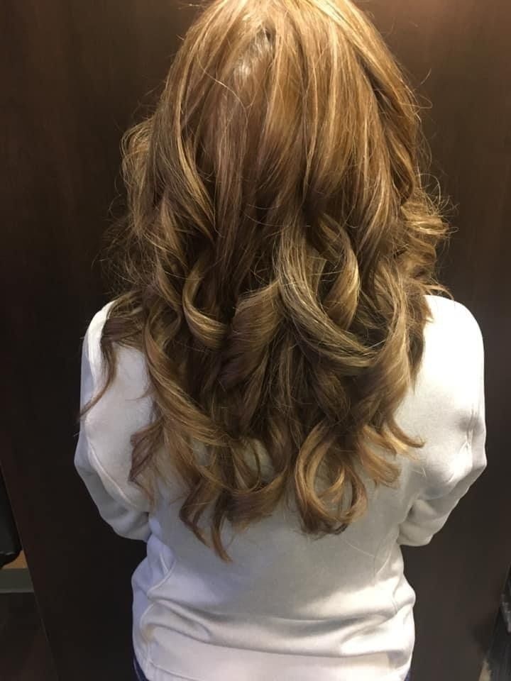 A woman with long brown hair is wearing a white shirt.