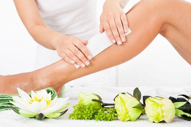 Leg being waxed with a strip in a spa-like setting with flowers.