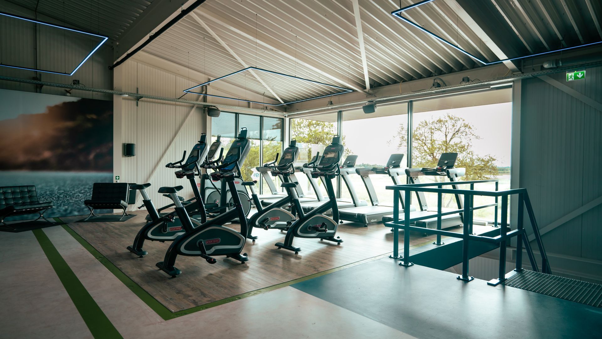 Lege, moderne sportschool met loopbanden en hometrainers onder heldere dakramen.