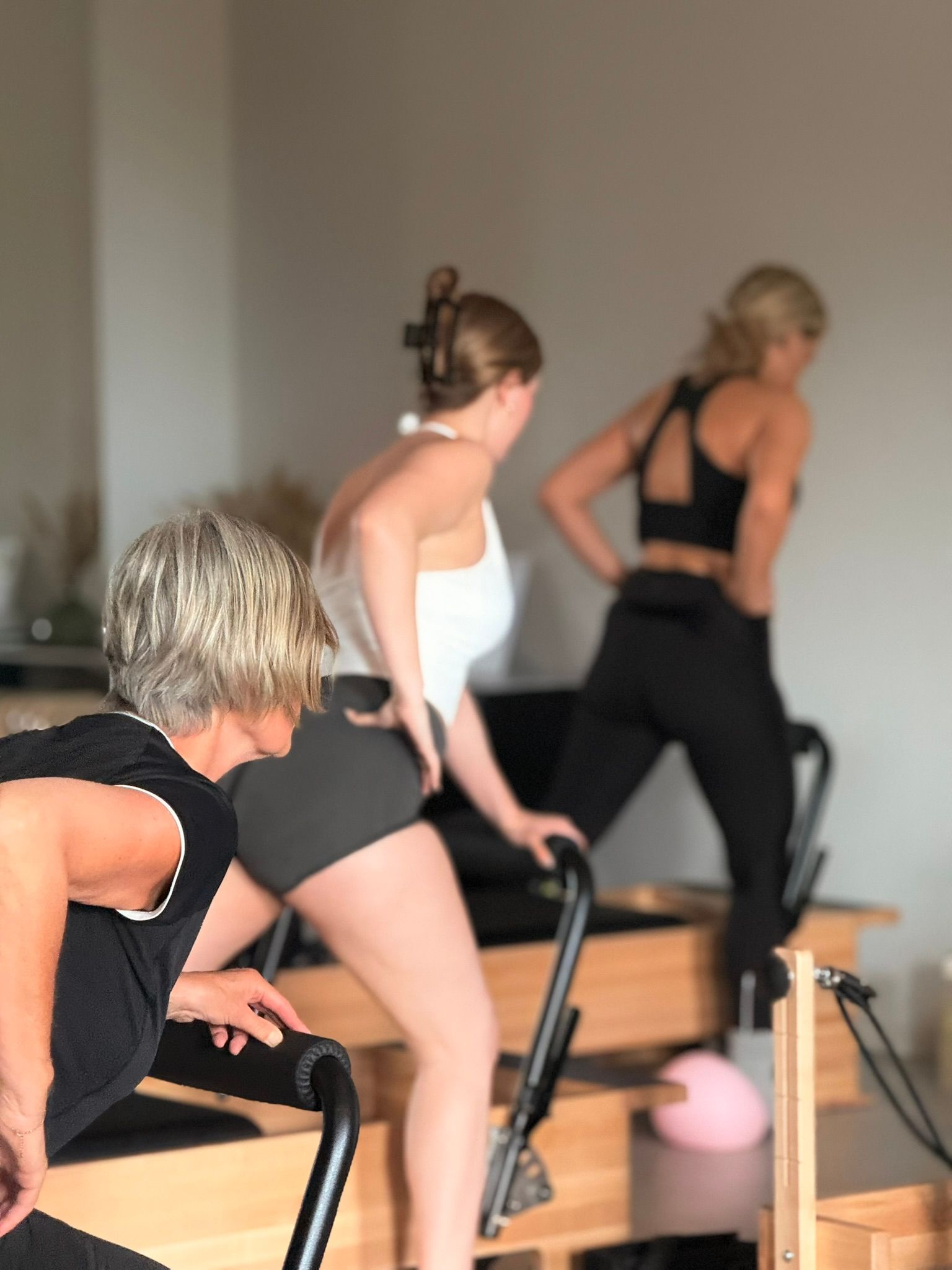 Mensen die oefeningen doen op reformer pilatesapparaten in een studio.