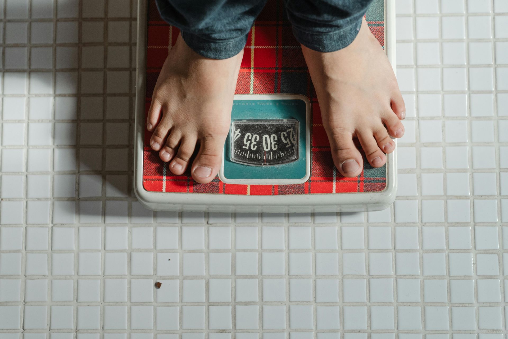 man standing on weighing scales to check progress of nutritionist weight management programme