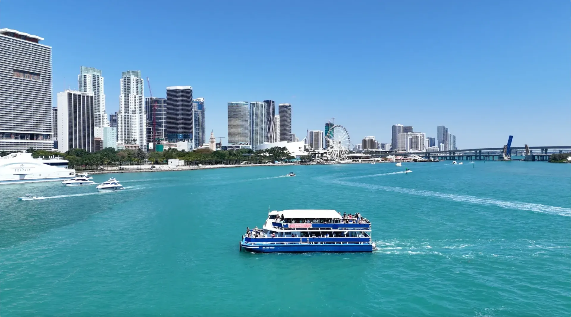 Clear weather over Biscayne Bay with the Downtown Miami skyline and a sightseeing boat on calm water.