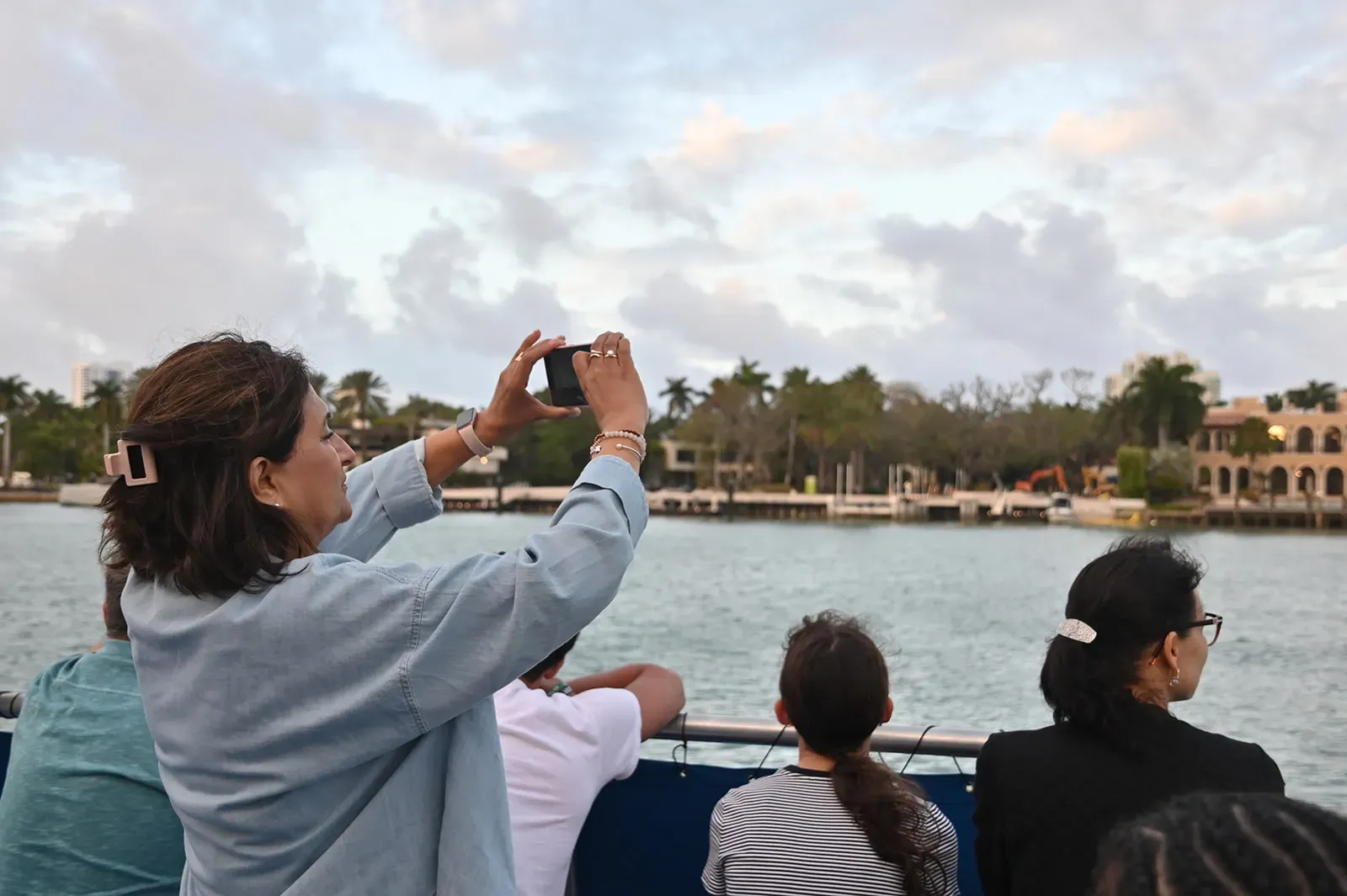 family taking photos of waterfront homes during a boat tour in Miami on Biscayne Bay