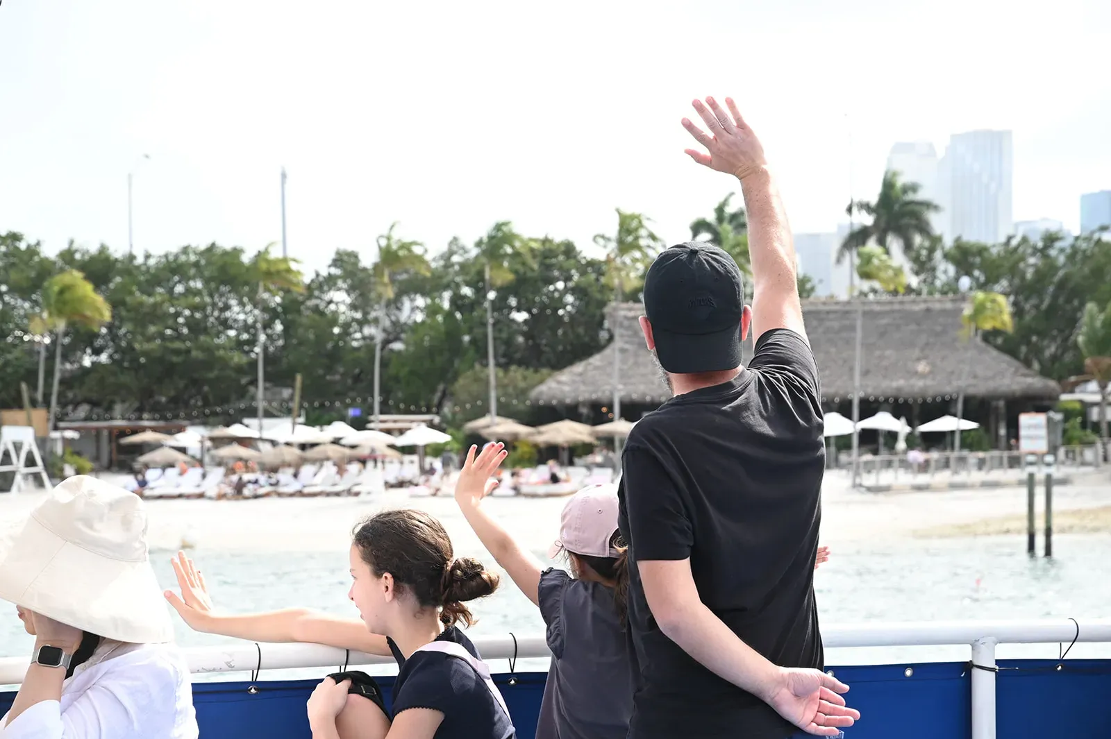 Families waving toward Jungle Island and Joia Beach while cruising along the waterfront route near Watson Island in Miami.