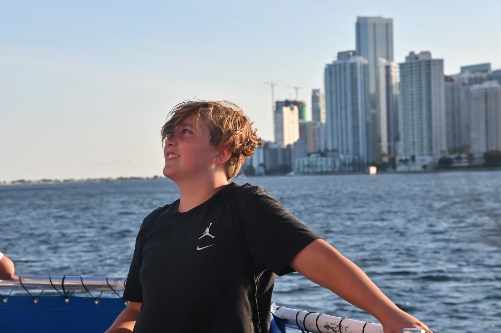 A young guest enjoying the family-friendly Biscayne Bay boat tour route with Miami's waterfront in the background.