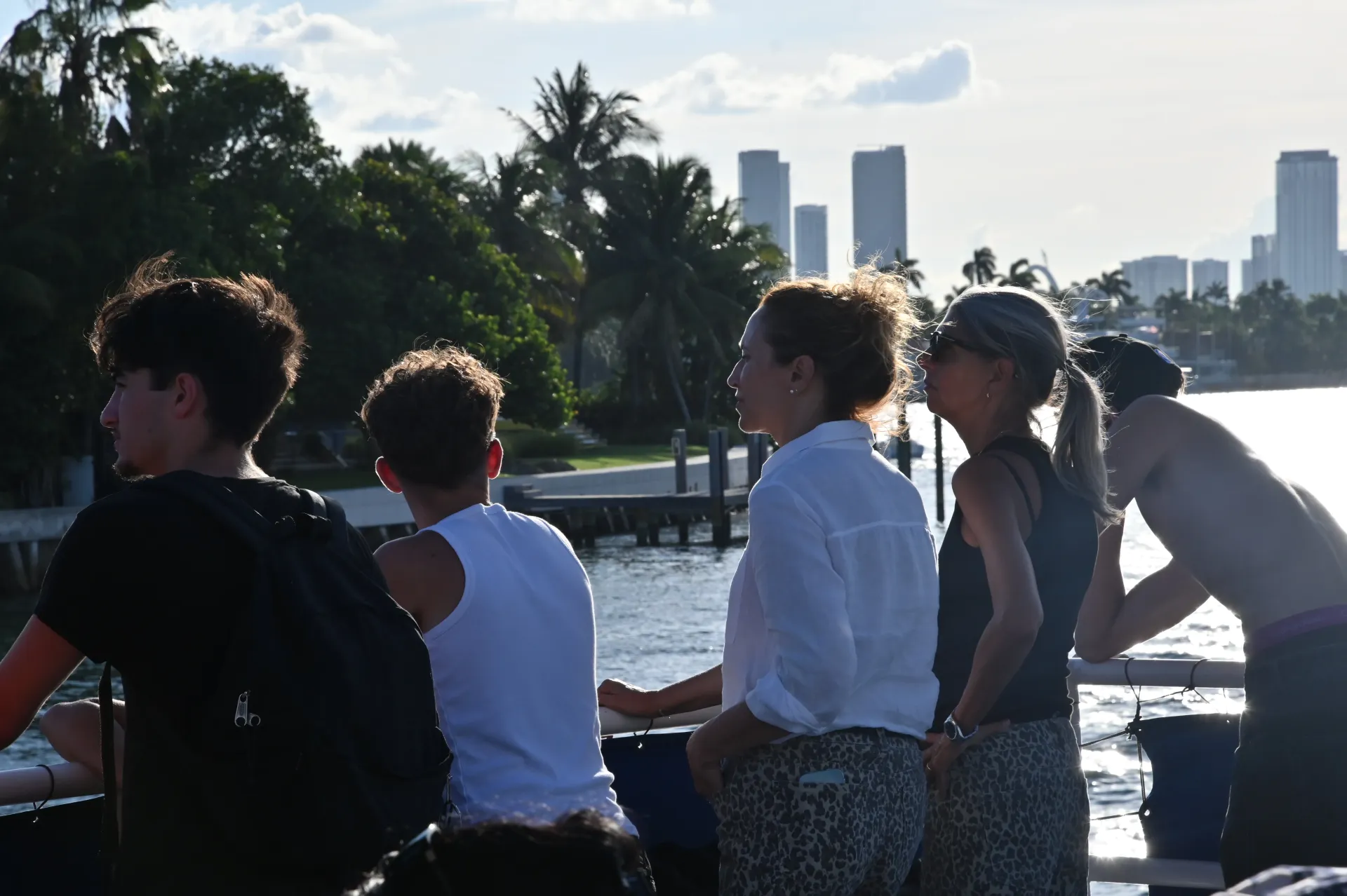 Guests cruising past the Mansions of Miami Beach route along Biscayne Bay with waterfront estates and the Downtown Miami skyline in the distance.