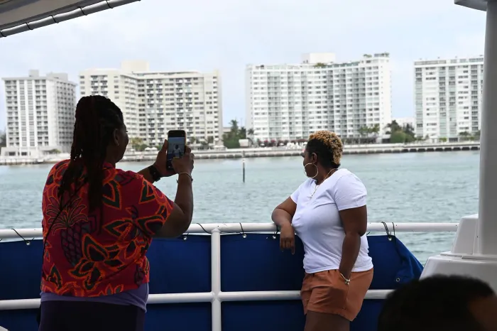 Miami boat tour guests taking photos of celebrity homes on Biscayne Bay during sightseeing cruise