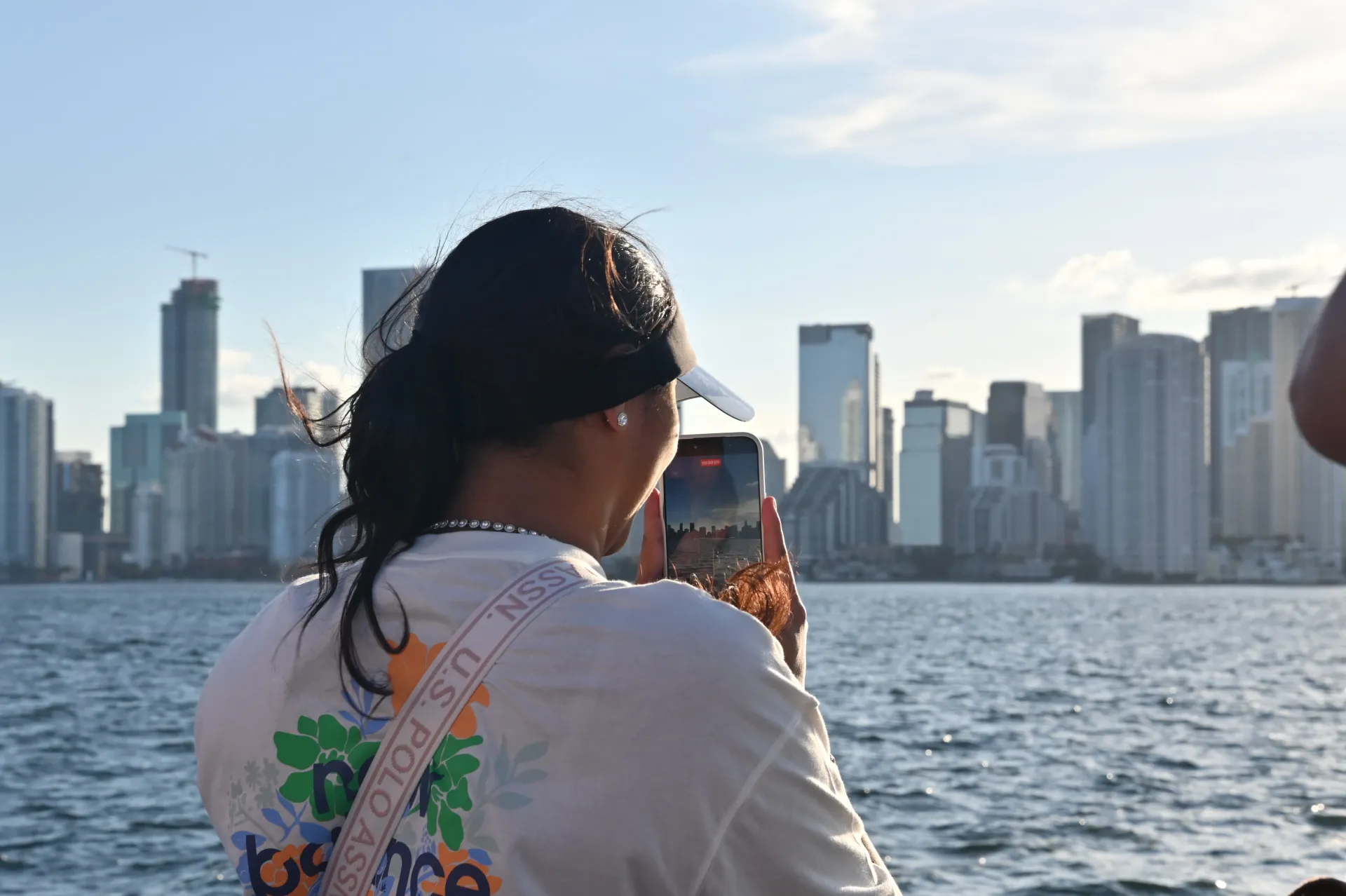 Guest photographing the Miami skyline during a sightseeing boat cruise on Biscayne Bay.