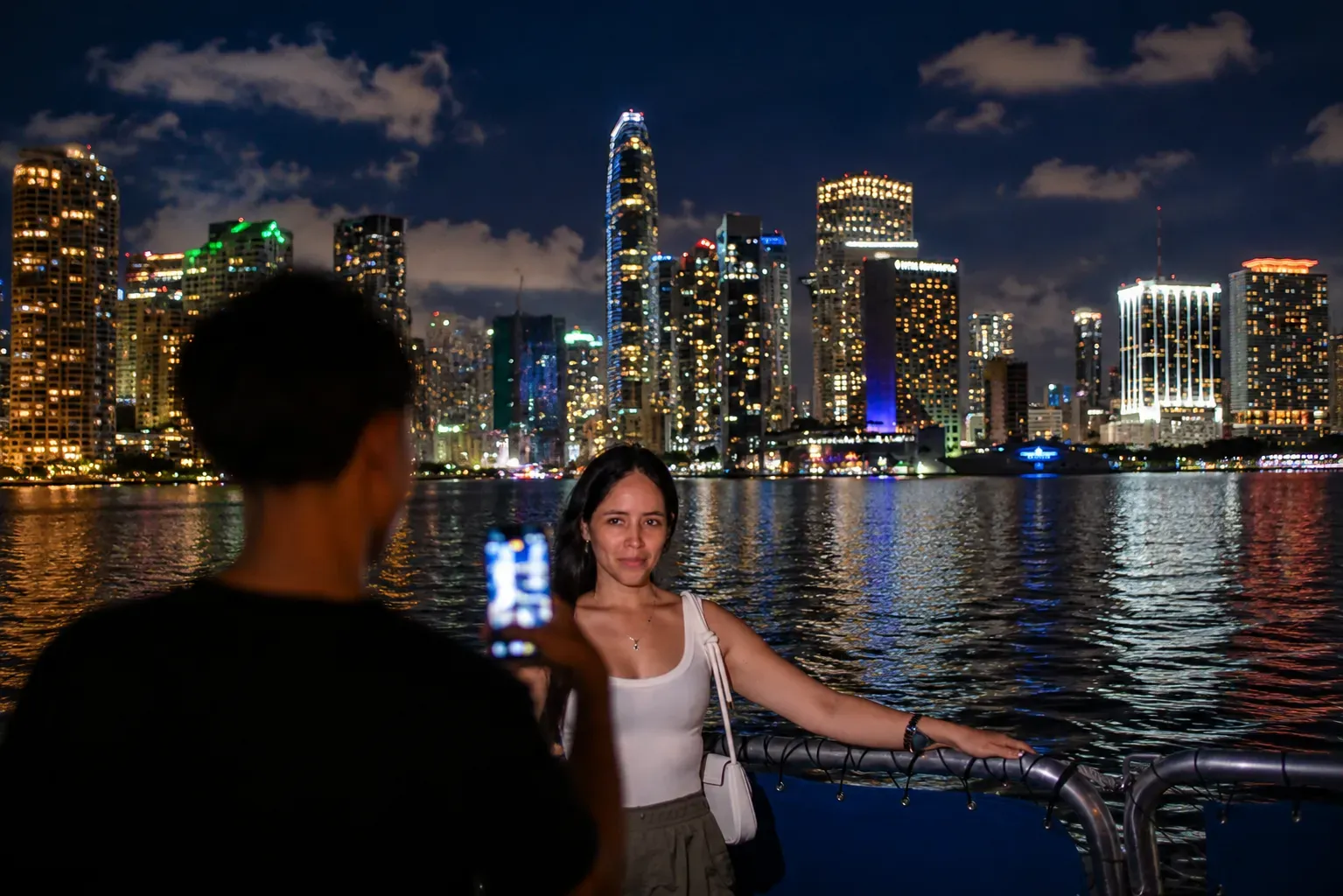 Woman enjoying a Miami Skyline Cruise at Night with Downtown Miami skyline reflections across Biscayne Bay