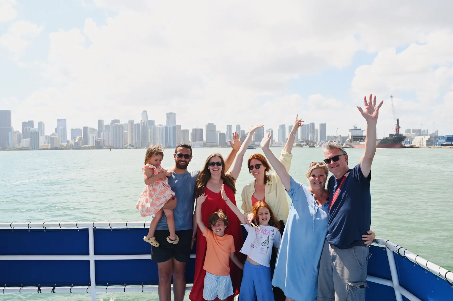 Family posing aboard a sightseeing cruise with the Miami skyline stretching across Biscayne Bay in the background.