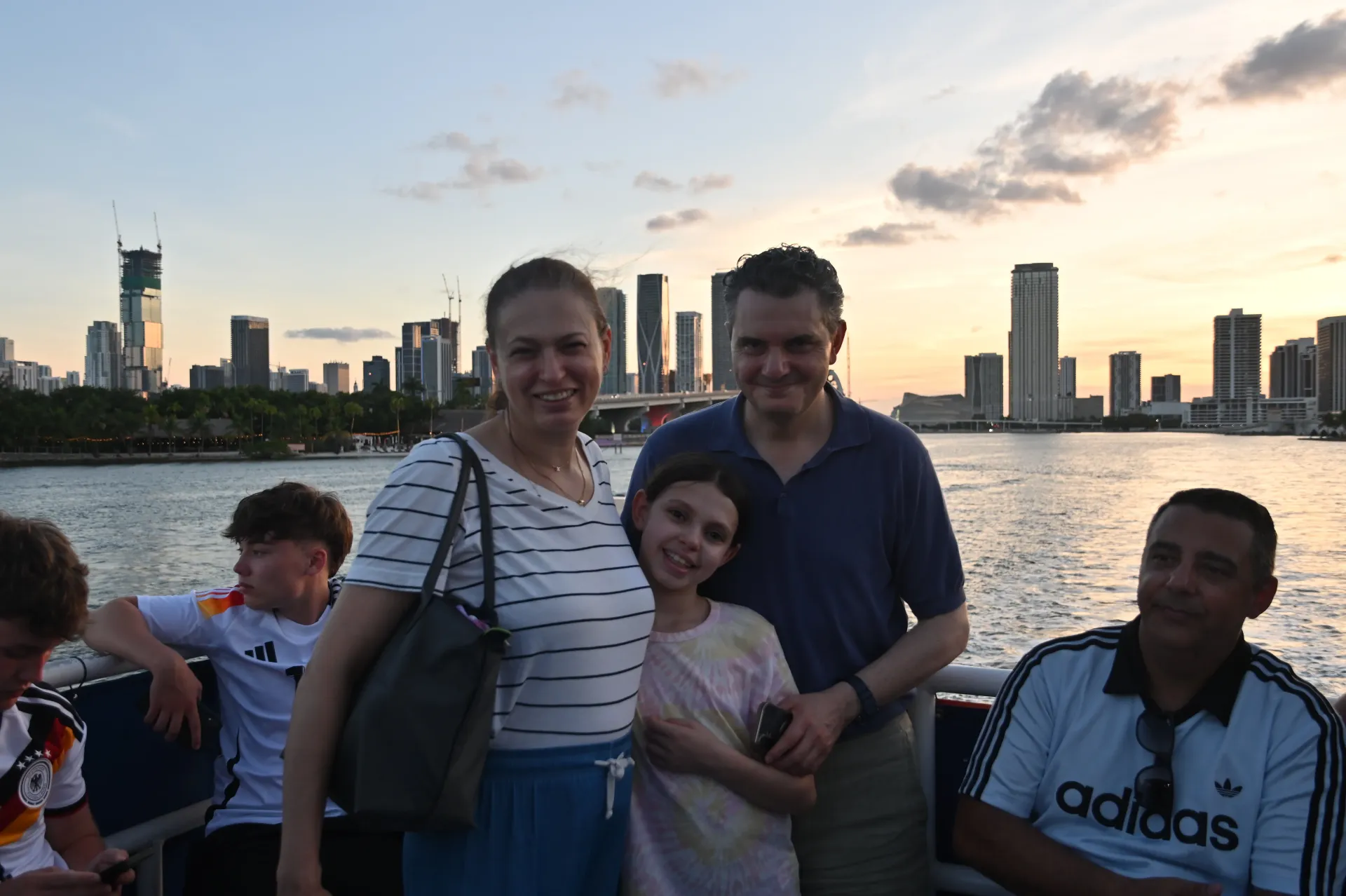 Family enjoying a Miami sunset boat experience with the Downtown Miami skyline glowing during golden hour.