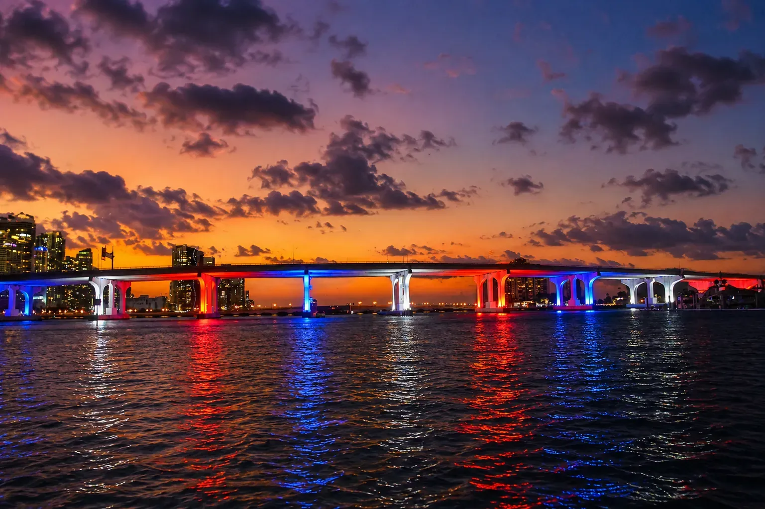 Miami twilight cruise view of the colorful MacArthur Causeway bridge reflecting on Biscayne Bay