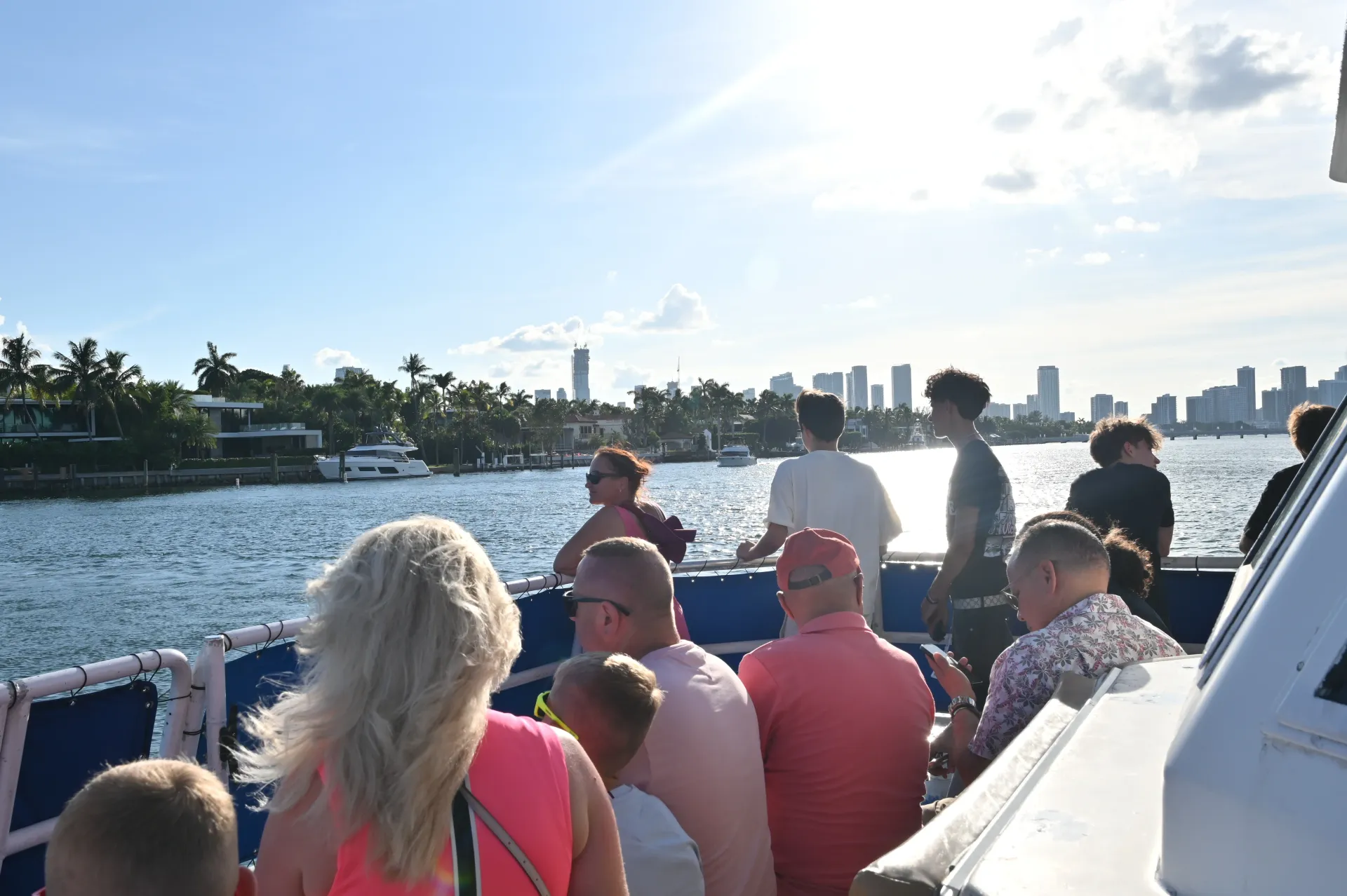 Passengers enjoying the open-air upper deck as the sightseeing route passes Miami's waterfront homes and Biscayne Bay.