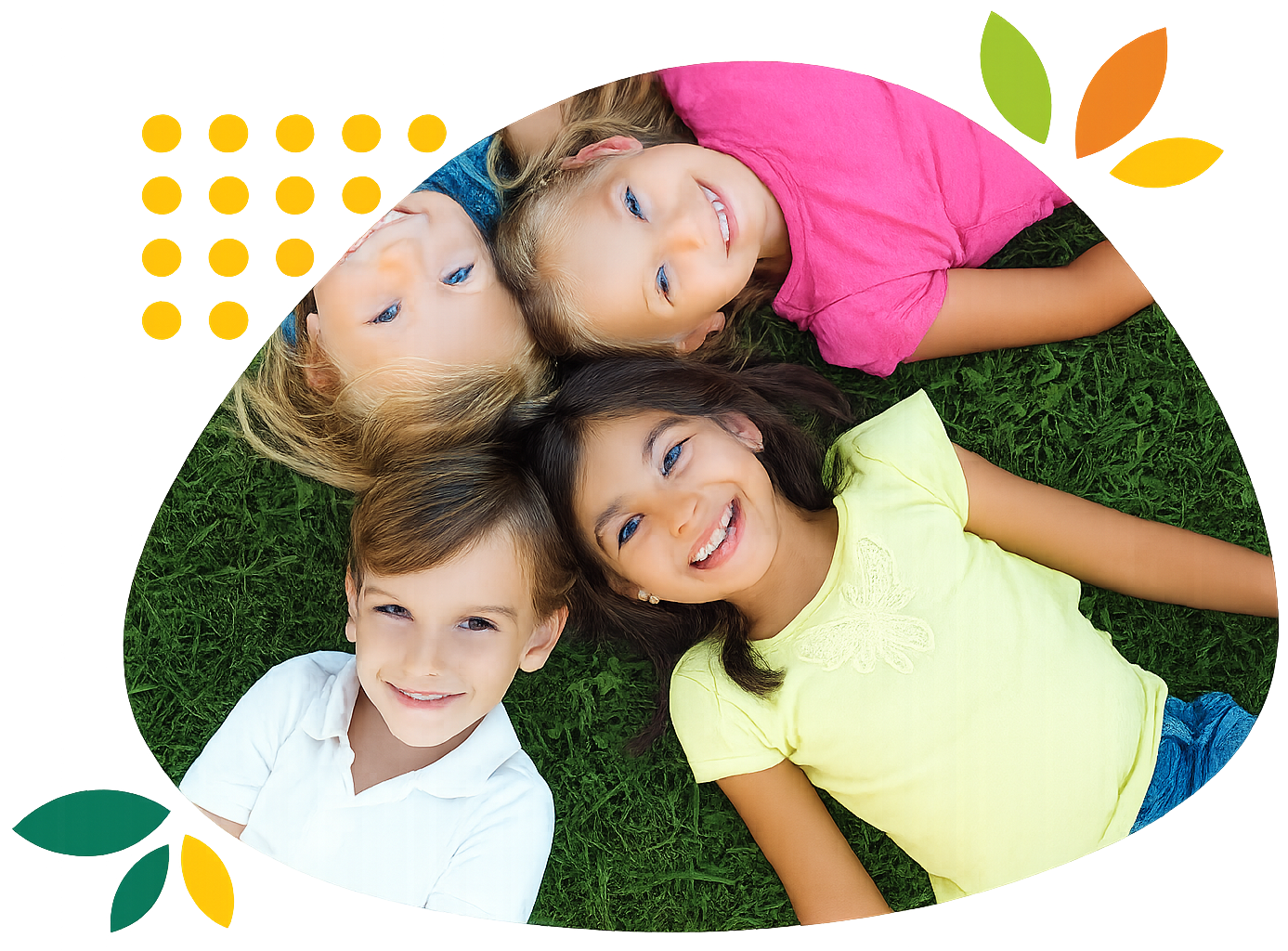 Three children are laying in a circle on the grass and smiling