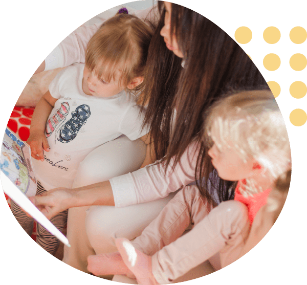 A woman is reading a book to two little girls
