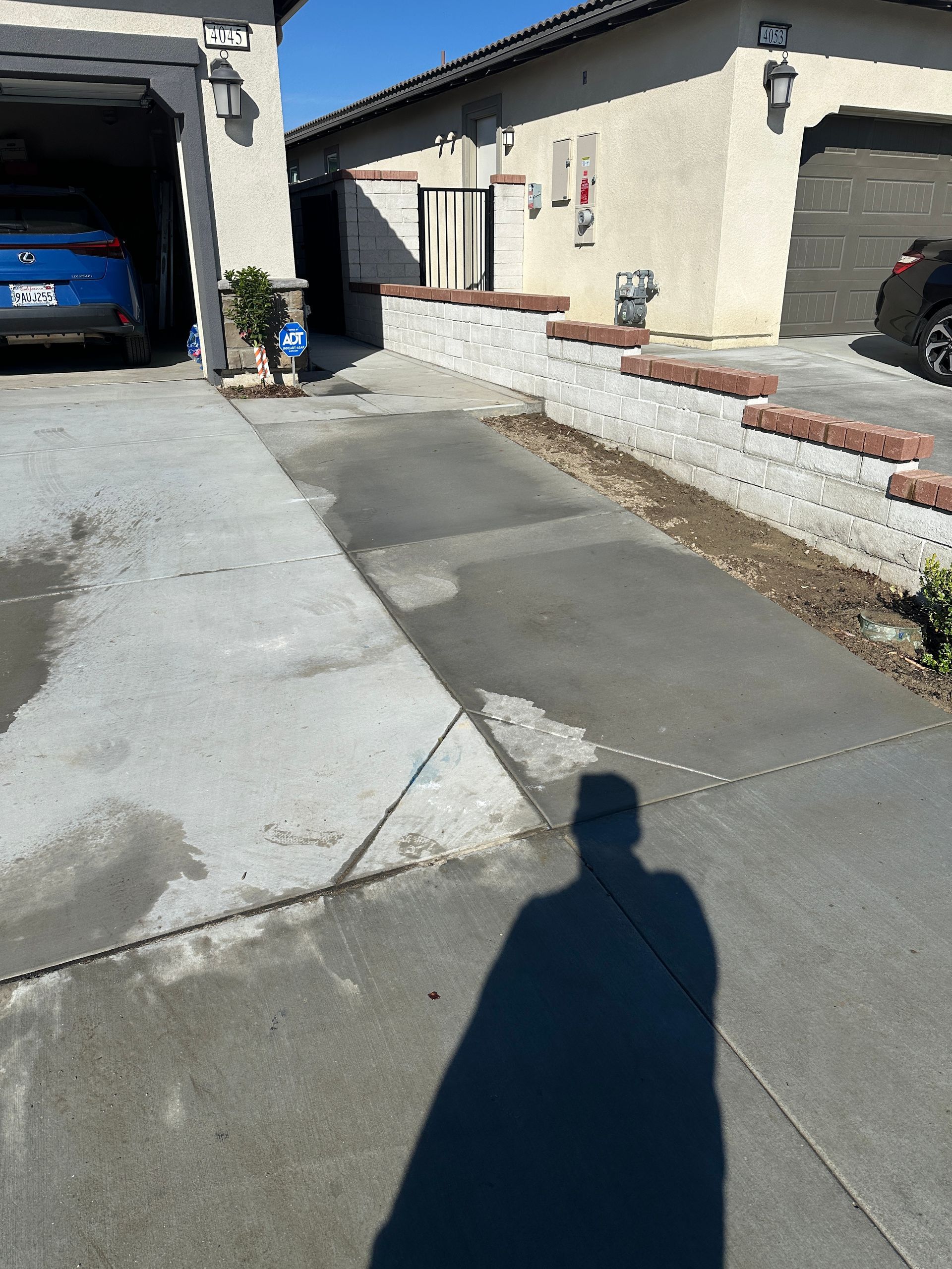 Gloved hands laying gray cinder blocks in a masonry wall outdoors
