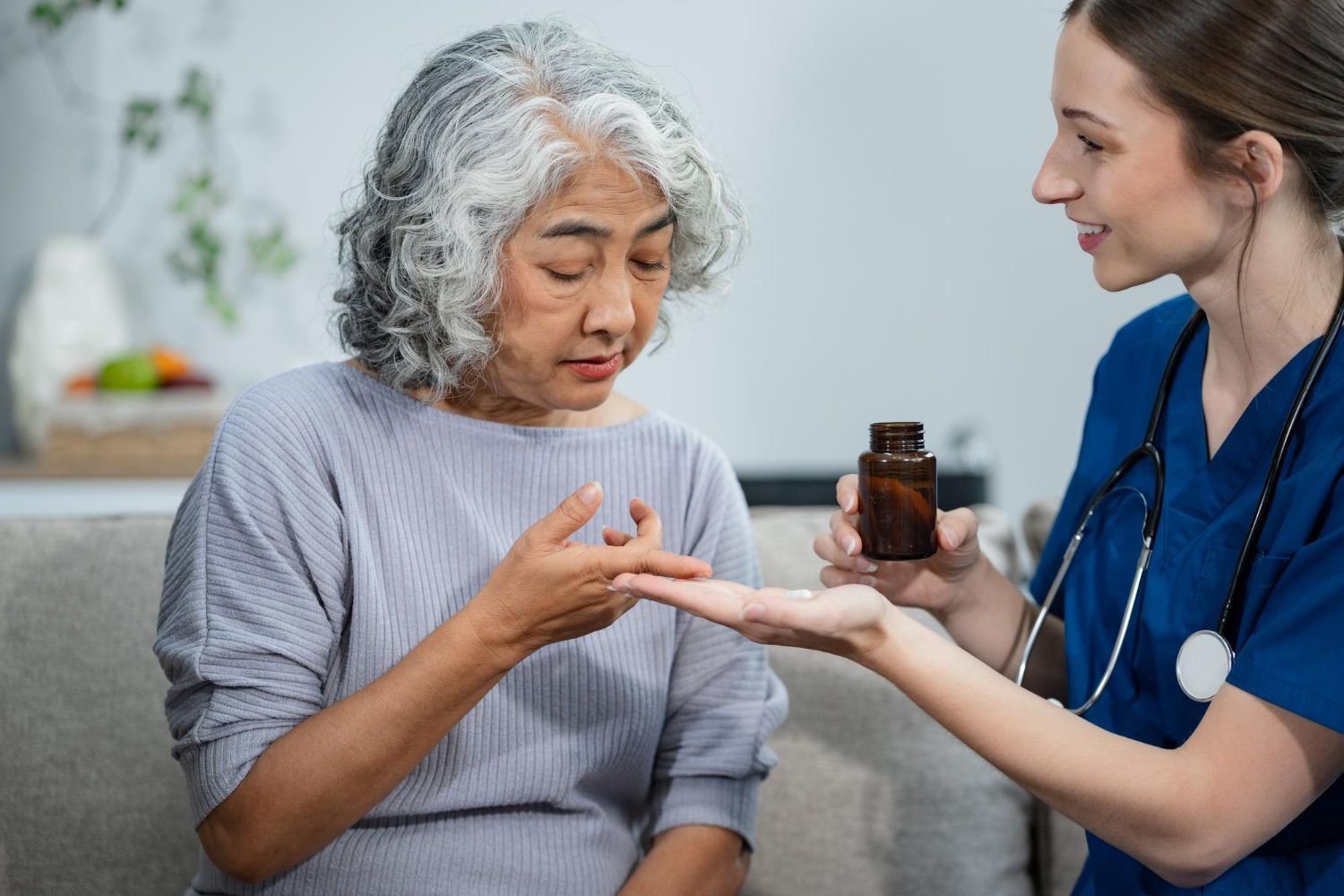Nurse handing a medicine bottle to a seated patient, with the patient examining pills in a bright clinic.