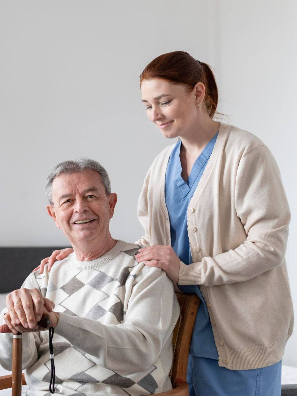 A nurse is standing next to an elderly man in a wheelchair.