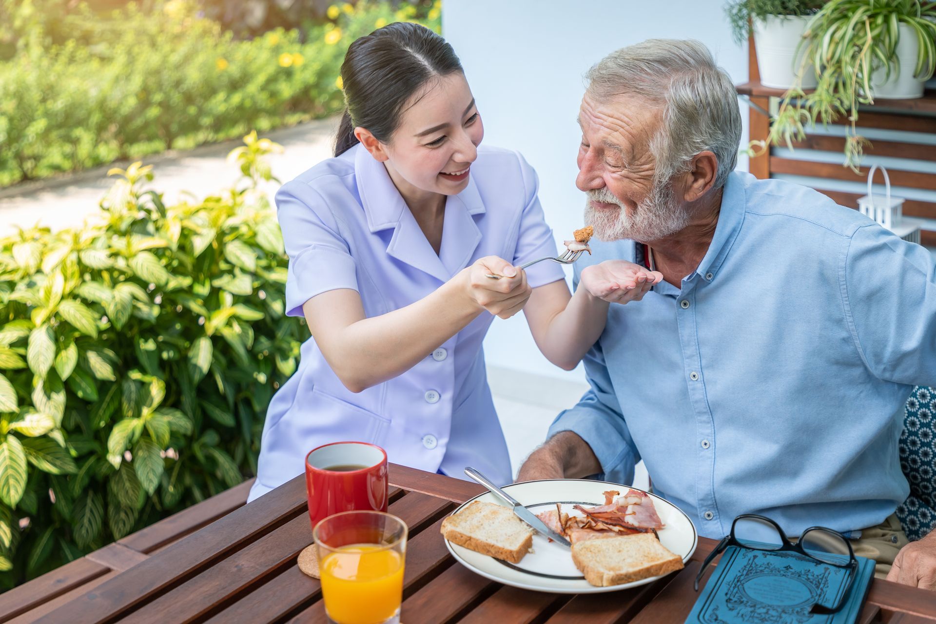 nurse feeding elderly man at home