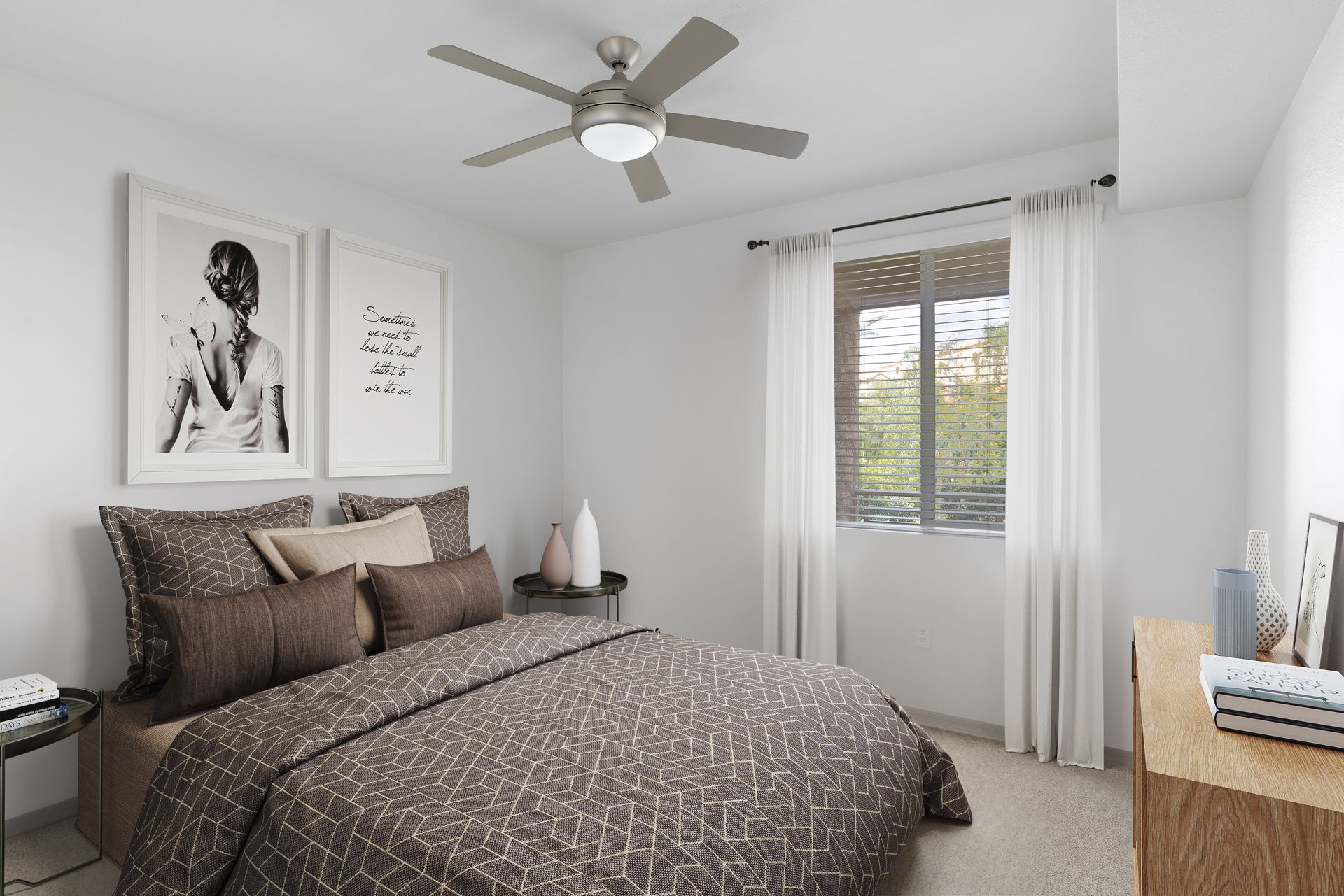 Bedroom in a modern apartment with a bed, dresser, window with blinds, and a ceiling fan.