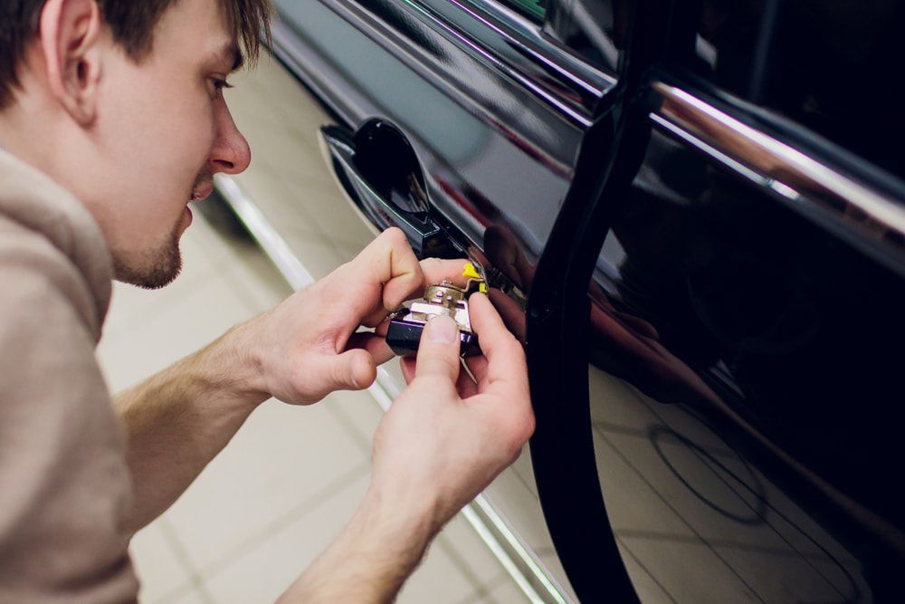 A Man is Opening a Car Door With a Key — Coast & Hinterland Mobile Locksmiths In Cooroy, QLD