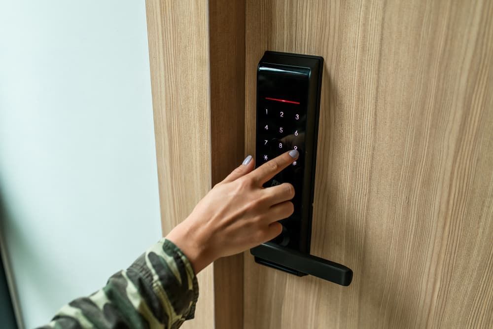 A Woman is Pressing a Button on a Door Lock — Coast & Hinterland Mobile Locksmiths In Tewantin, QLD
