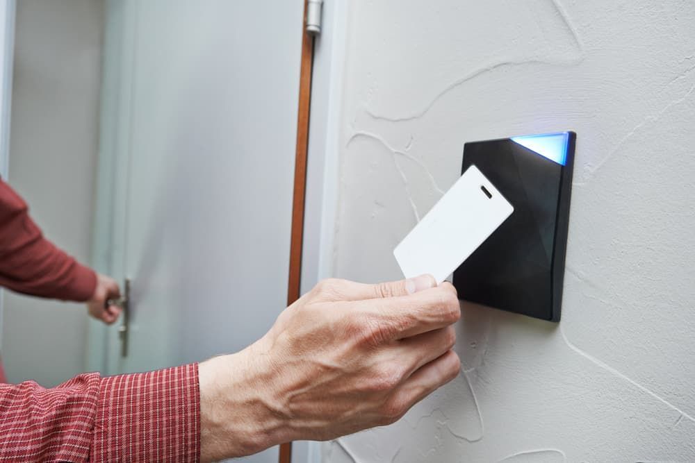 A Person is Holding a Key Card in Front of a Door — Coast & Hinterland Mobile Locksmiths In Noosaville, QLD