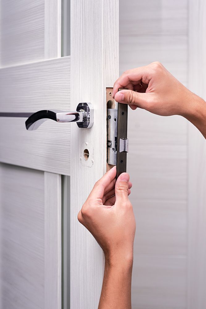 A Person is Installing a Door Lock on a White Door — Coast & Hinterland Mobile Locksmiths In Peregian, QLD