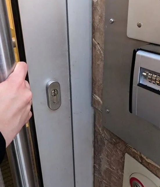 A Person is Opening a Door Next to a Key Safe — Coast & Hinterland Mobile Locksmiths In Tewantin, QLD