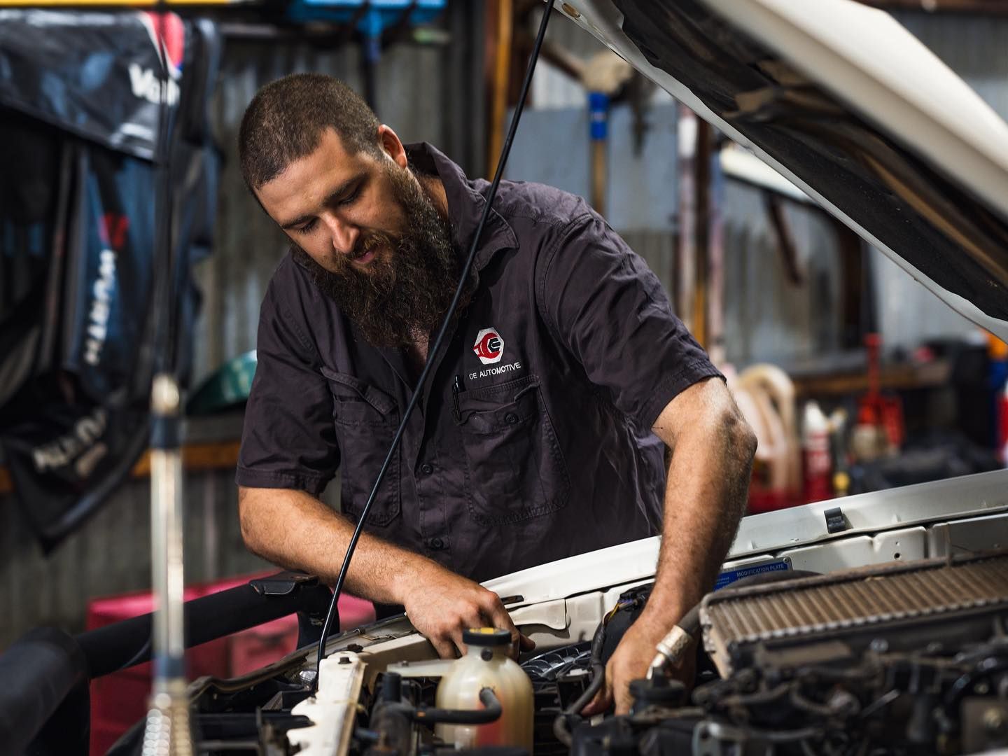 Mechanic With a Beard Working on a Car Engine in a Garage — CE Automotive Service Centre in Garbutt, QLD