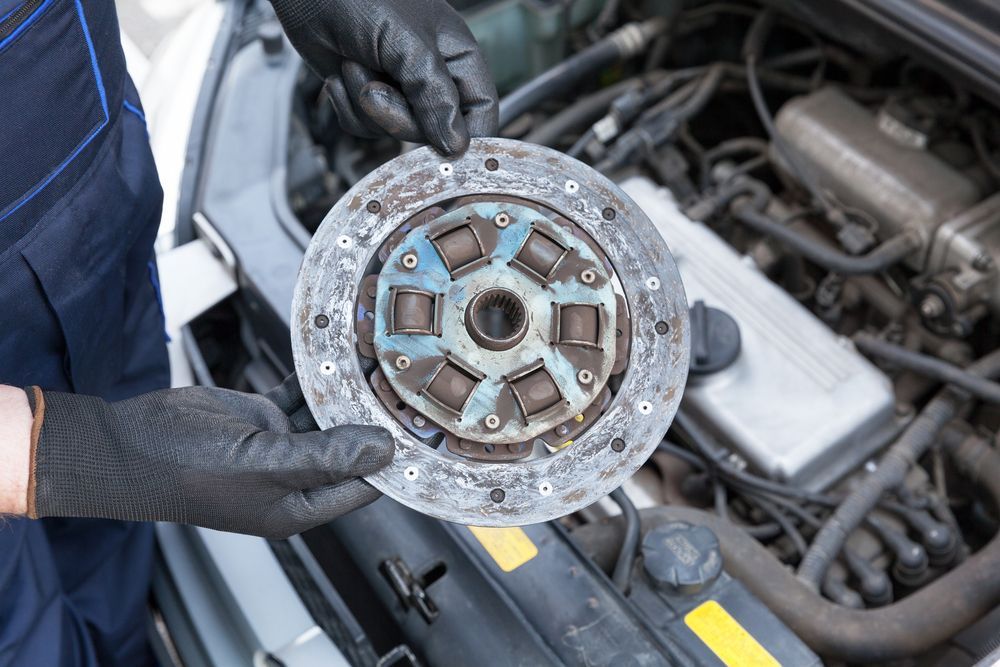 Mechanic Holding a Worn Car Clutch Disc — CE Automotive Service Centre in Garbutt, QLD