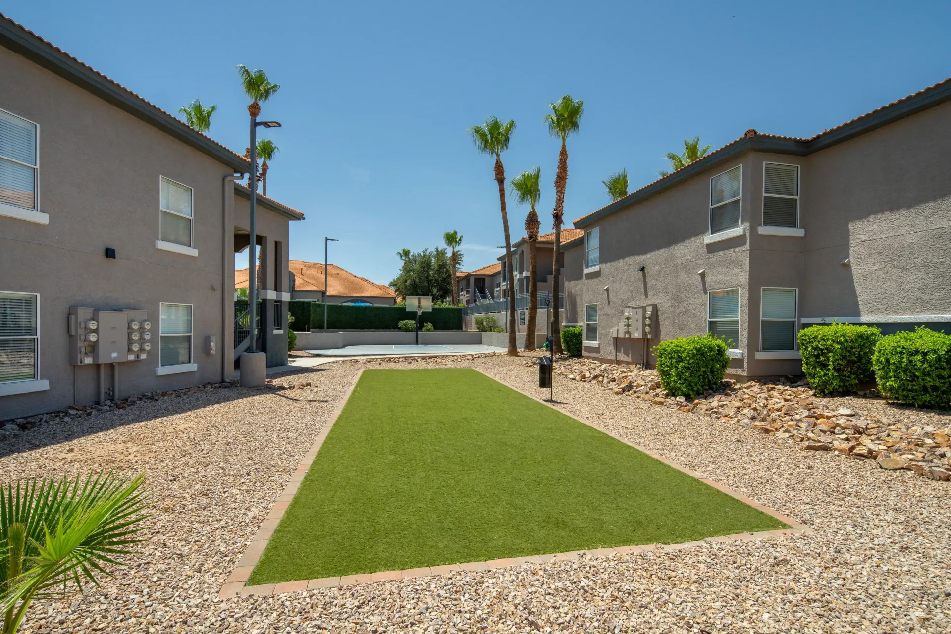 Outdoor area with a basketball court and green space, surrounded by apartment buildings at Sonoran Reserve in Tucson, AZ.