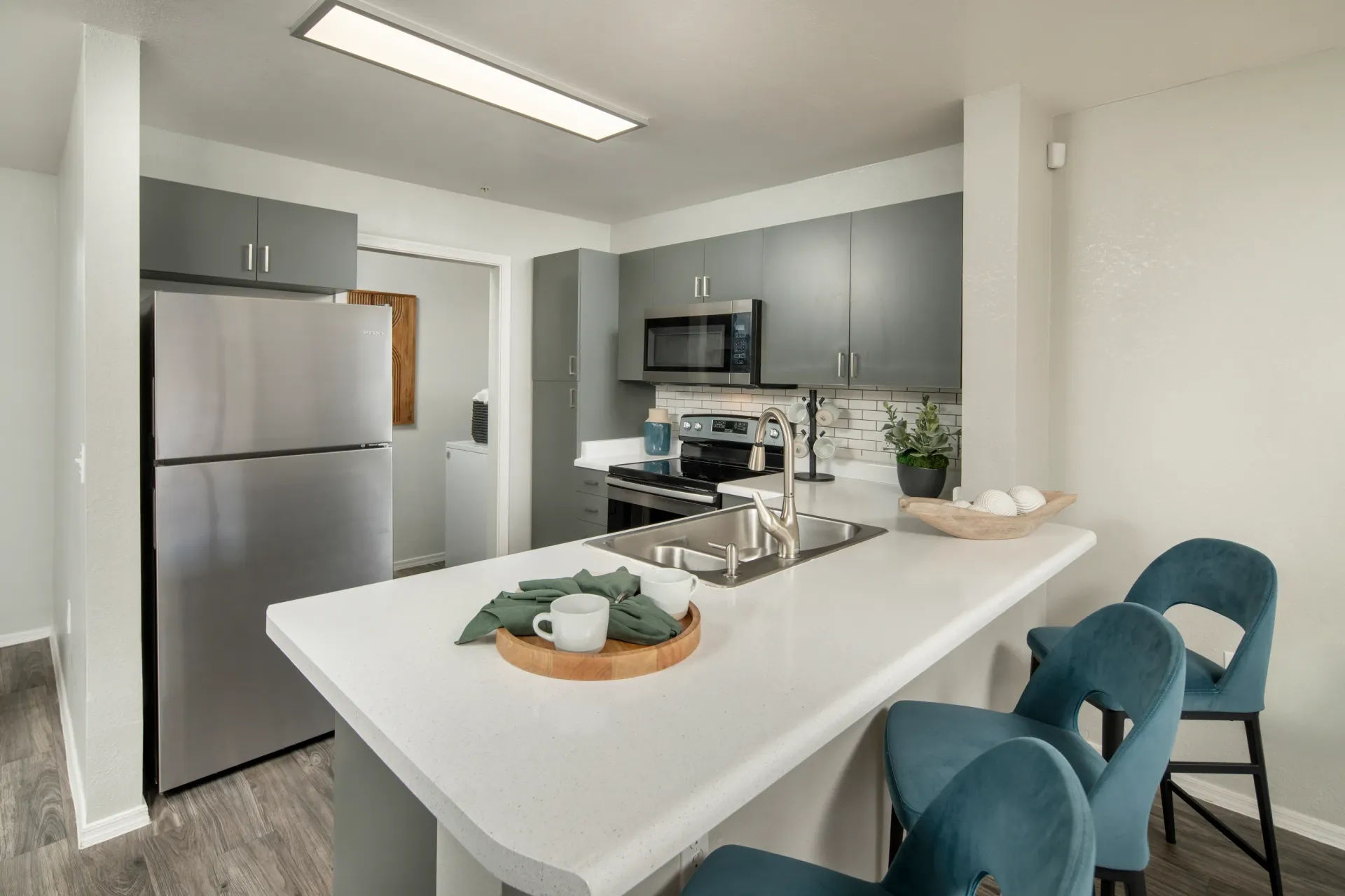 Modern kitchen with stainless steel appliances and a breakfast bar with bar stools at Sonoran Reserve in Tucson, AZ.