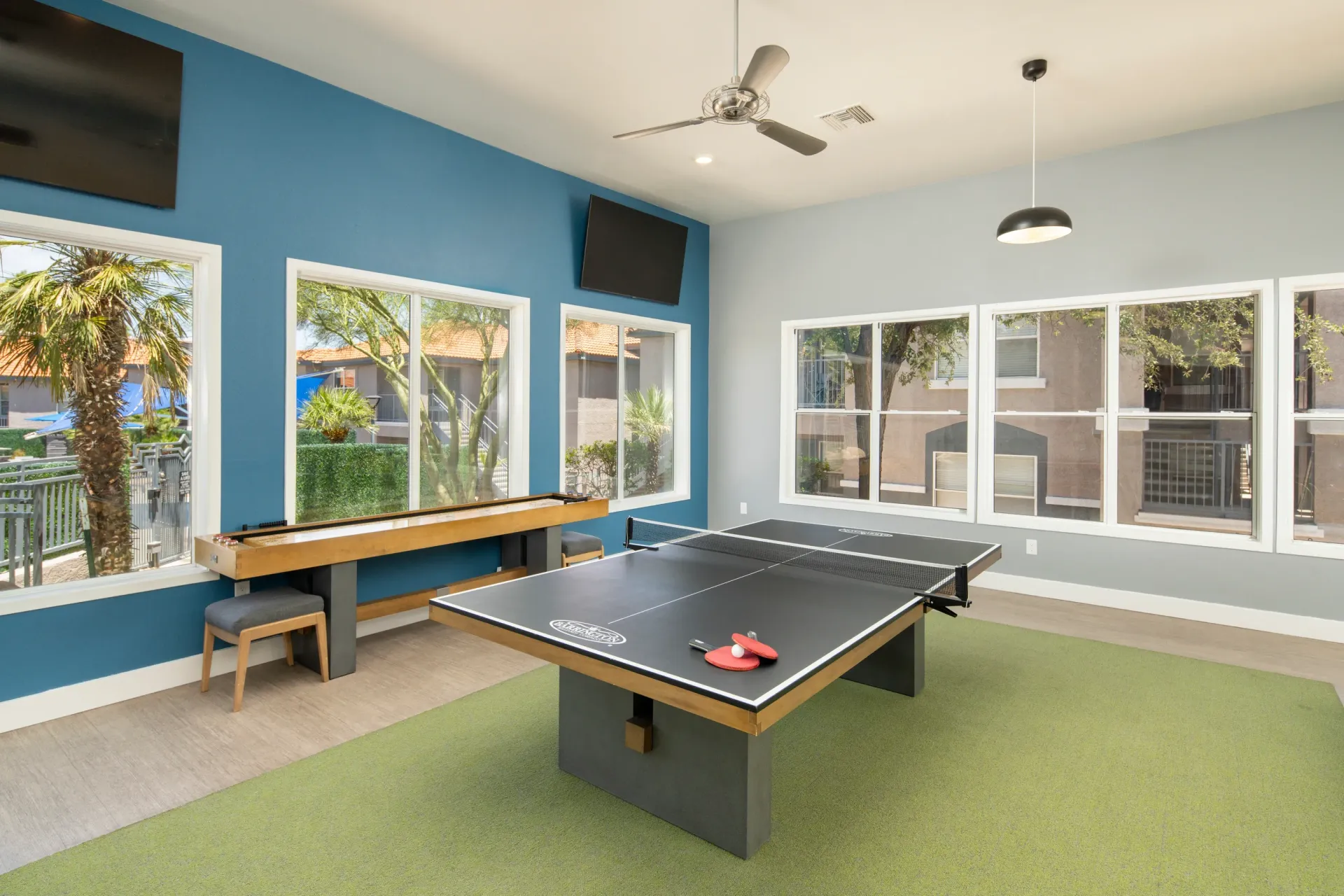 Ping pong table and shuffleboard in a community game room with large windows at Sonoran Reserve in Tucson, AZ.