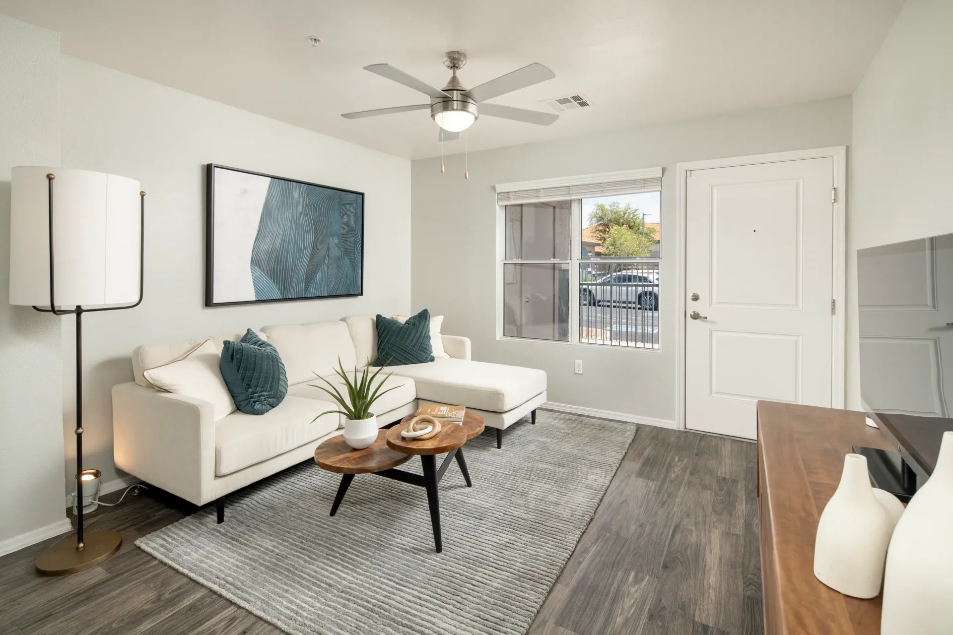 Living room with a sectional sofa, coffee table, and ceiling fan at Sonoran Reserve in Tucson, AZ.