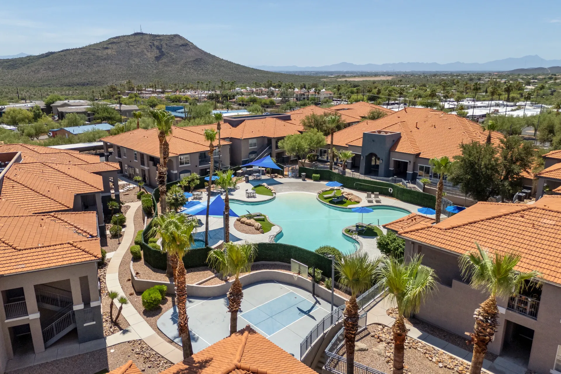 Aerial view of a resort-style pool and basketball court with desert mountain backdrop at Sonoran Reserve in Tucson, AZ.