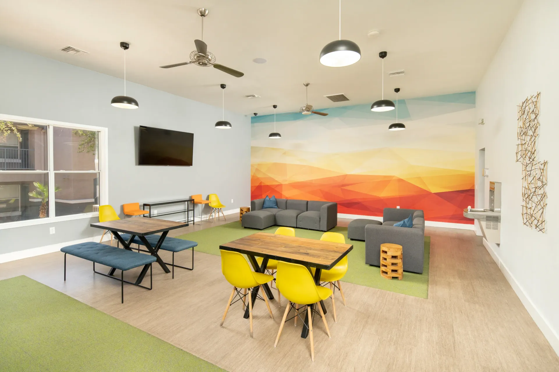 Modern lounge area with sofas, tables, chairs, and a colorful geometric mural at Sonoran Reserve in Tucson, AZ.
