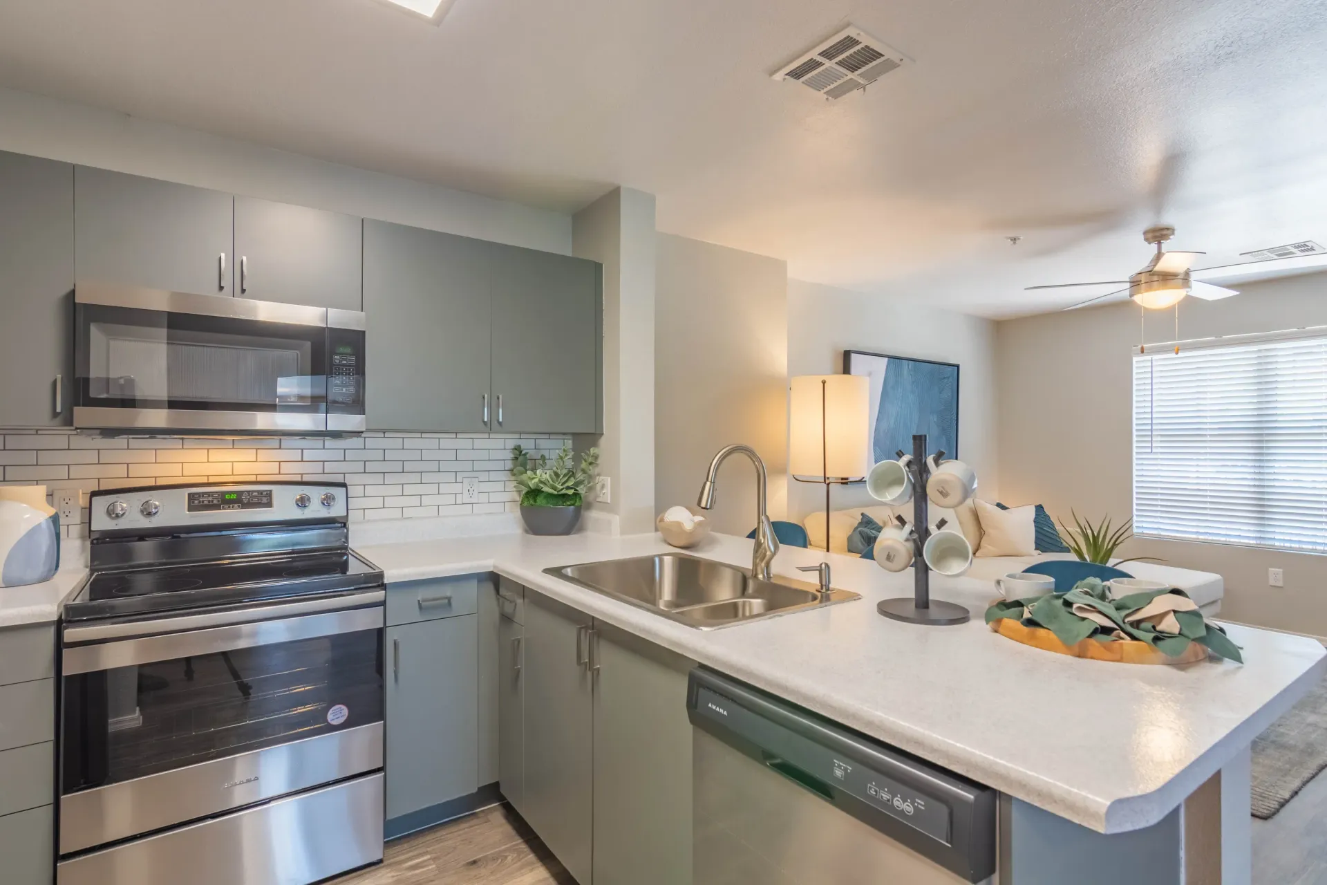 Modern kitchen with stainless steel appliances, gray cabinets, and subway tile backsplash.