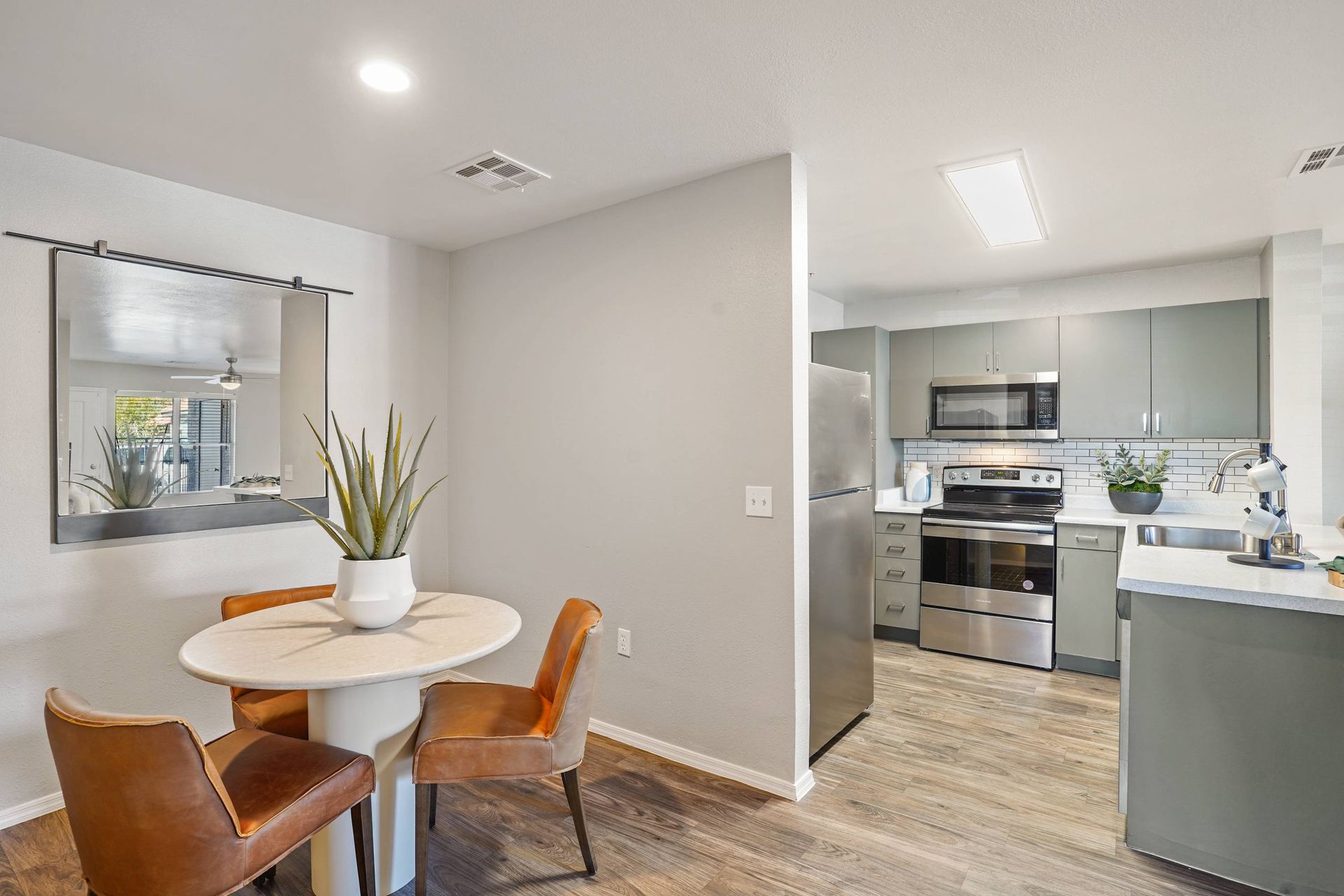 Dining area with a round table and brown chairs next to the modern gray kitchen. Take a closer look at our versatile 3-bedroom apartments in Tucson, AZ, by scheduling a tour today.
