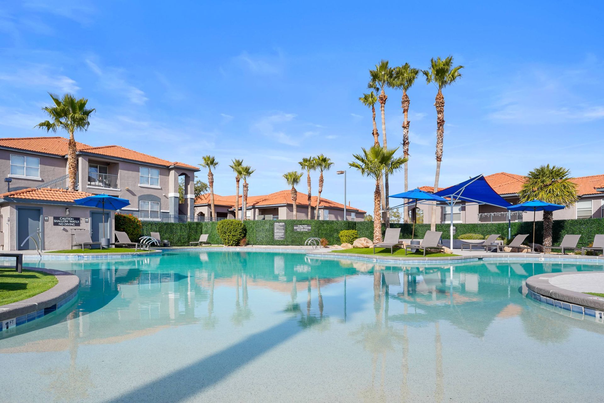 Outdoor apartment community pool with palm trees, lounge chairs, and blue shade umbrellas. Bring your furry companion along and tour our welcoming pet-friendly apartments in Tucson, AZ, at Sonoran Reserve.
