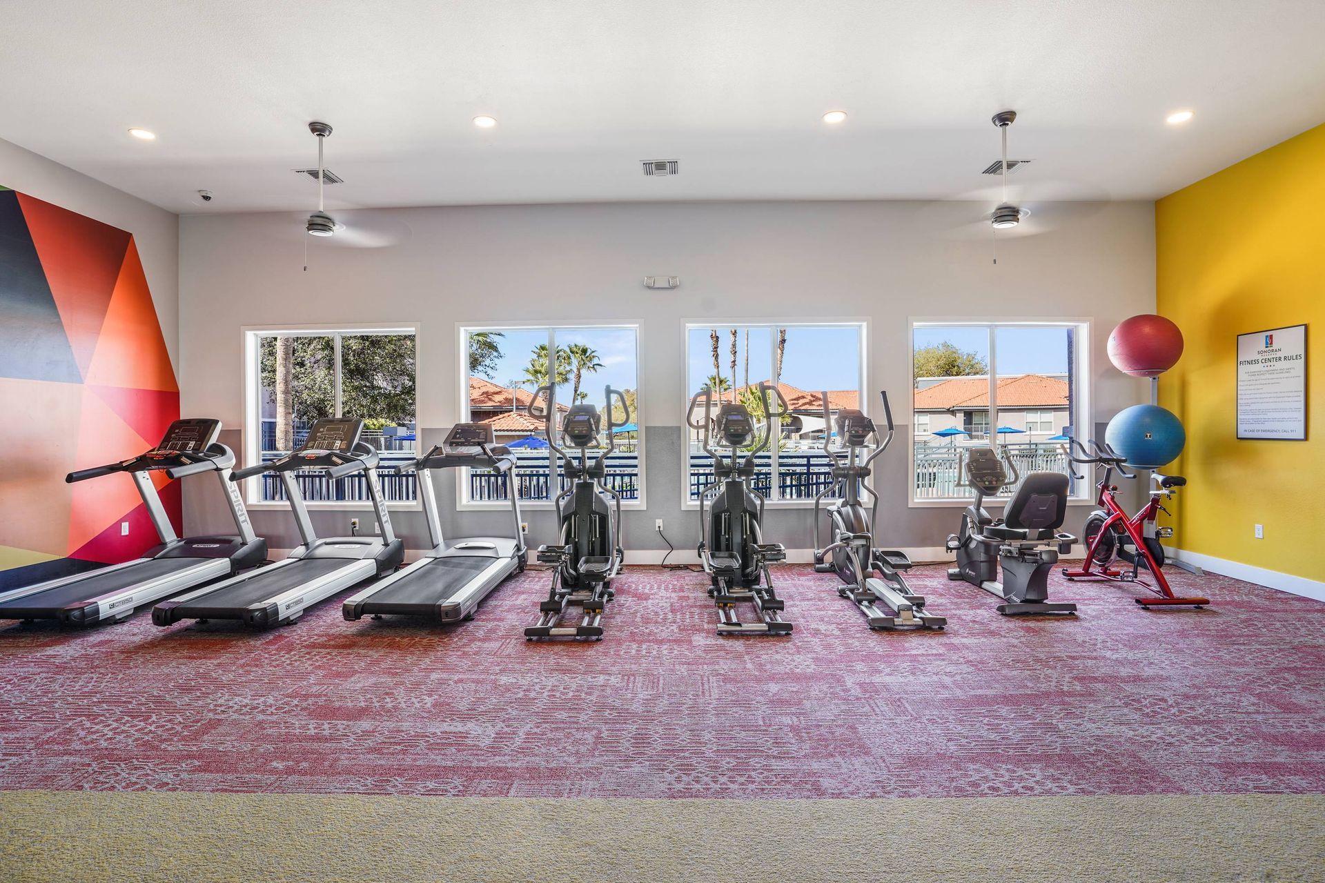 Indoor fitness center with cardio machines and large windows. Discover flexible living options when you tour our inviting 3-bedroom apartments in Tucson, AZ at Sonoran Reserve.
