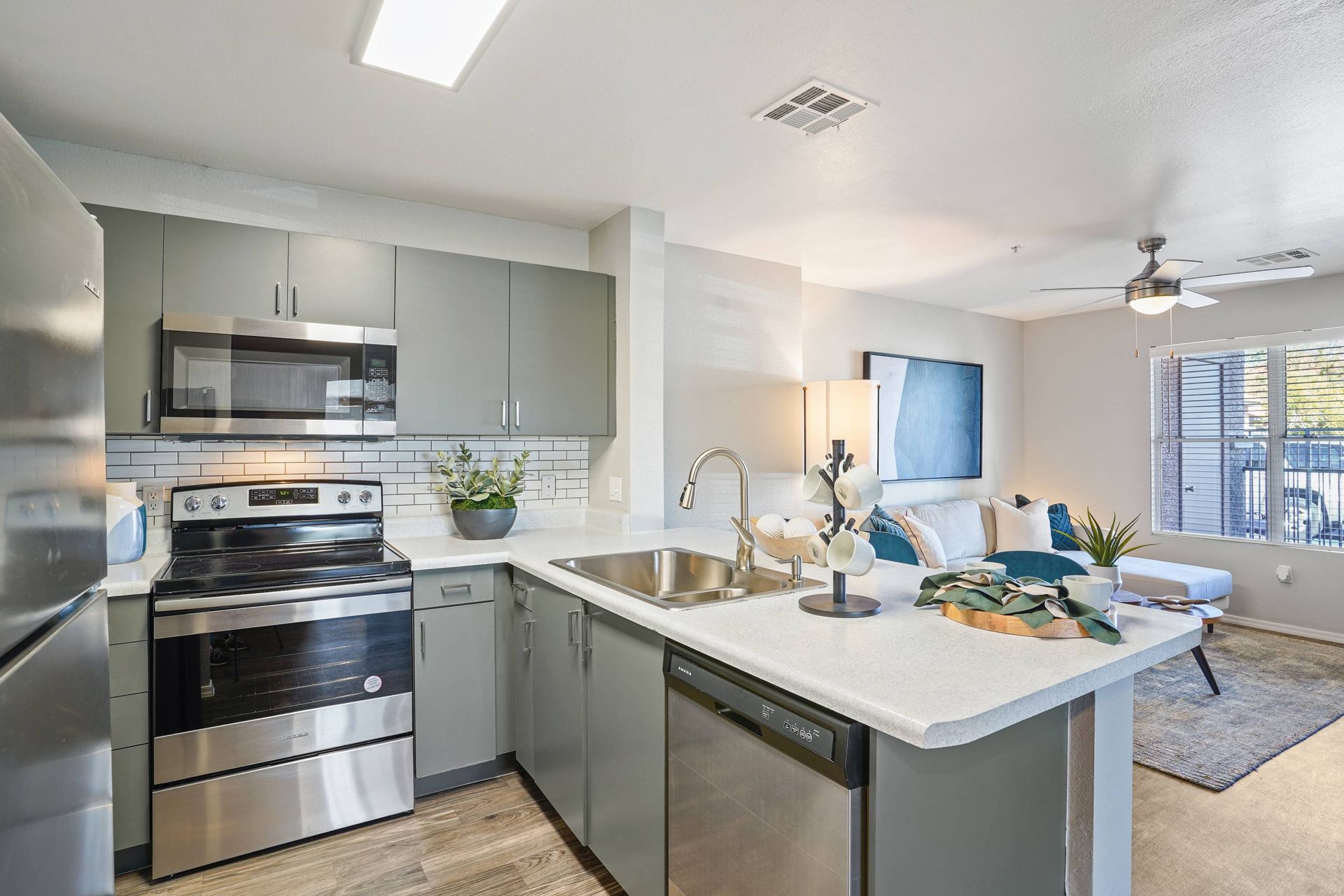 Open-concept kitchen with gray cabinets, stainless steel appliances, and a central island. Experience the comfort and convenience that make Sonoran Reserve stand out among Tucson, AZ rentals.