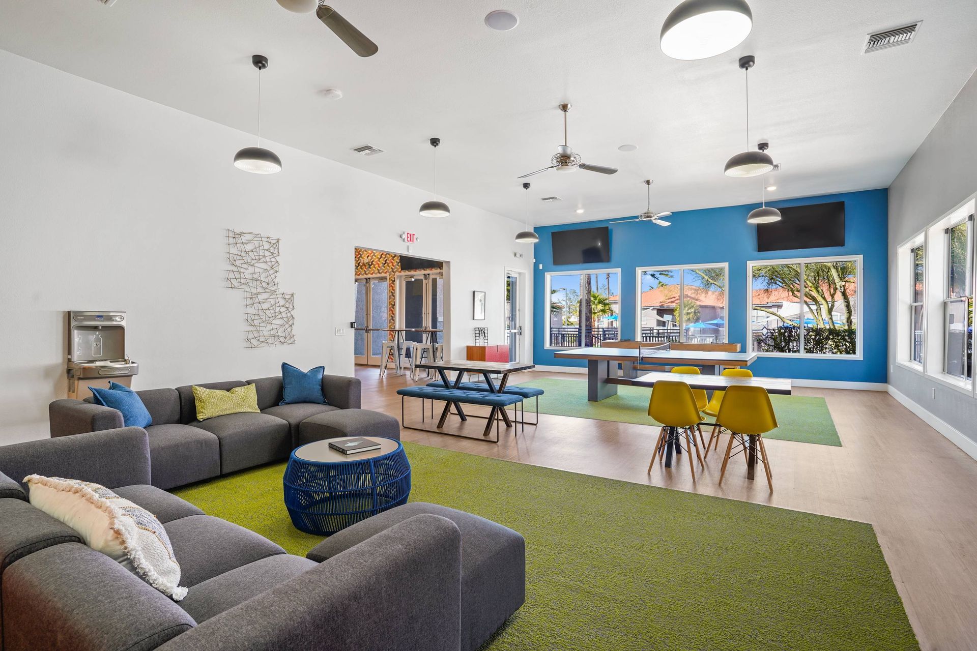 Interior community lounge with gray sectional sofas, colorful accents, tables, and large windows. Take a closer look at Sonoran Reserve and see why our Tucson, AZ apartments for rent are designed for modern living and everyday ease.
