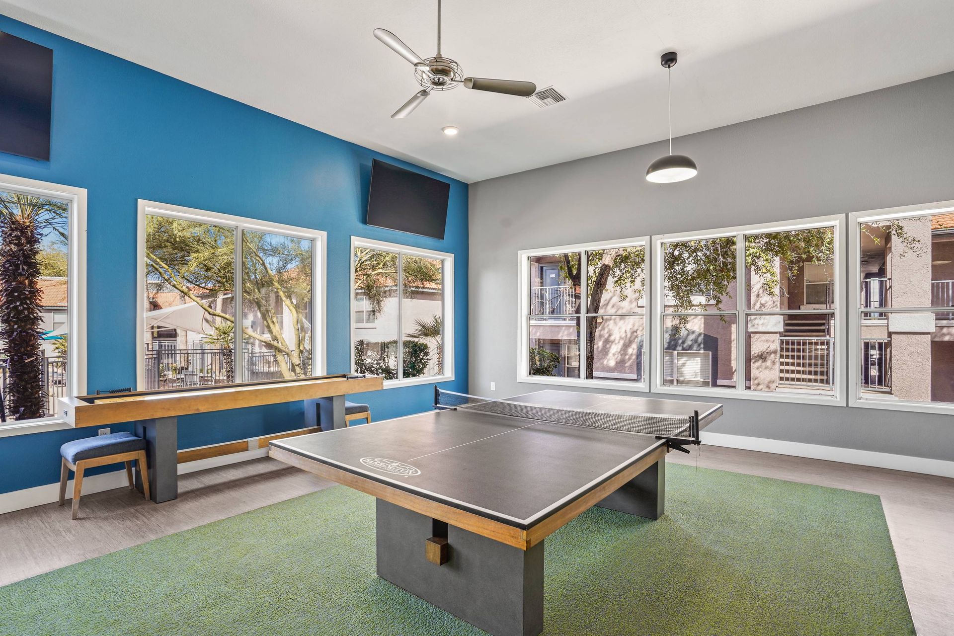 Indoor community recreation room with a ping-pong table, bench seating, and large windows.  Experience the lifestyle waiting for you at Sonoran Reserve—come tour our thoughtfully designed Tucson, AZ apartments today.
